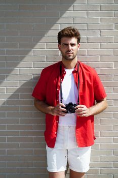 Millennial man traveling with a SLR camera outdoors