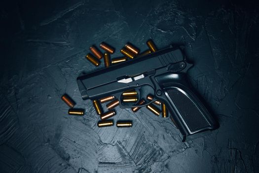 Flat lay of pistol and bullets. Firearms on dark background. Gun for defense or attack. Concept of crime ammunition and physical evidence. Weapons on concrete table.