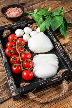 Mozzarella cheese, basil and tomato cherry in wooden tray, Caprese salad. wooden background. Top view.