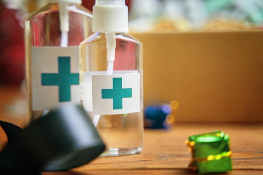 Two sanitizers with turquoise cross logo on wooden table. Concept of hand hygiene and prevention from viruses and bacteria. Christmas quarantine decorations and antiseptic.