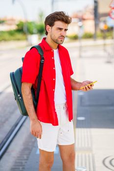 Student male waiting for a train at an outside station