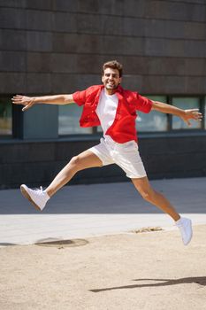 Young man wearing casual clothes jumping in urban background.