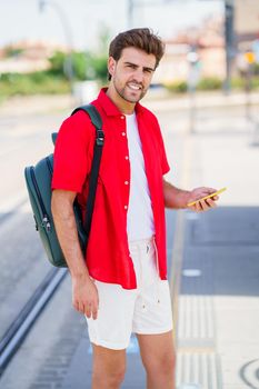 Student male waiting for a train at an outside station