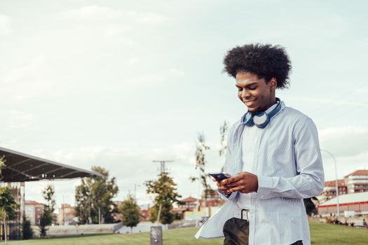 Portrait of afro guy using smartphone outdoors