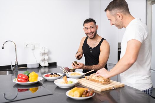 Gay couple cooking healthy vegan food together at home. Homosexual relationship concept.