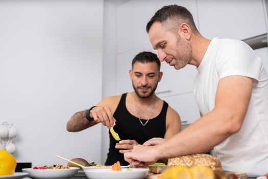Gay couple cooking healthy vegan food together at home. Homosexual relationship concept.