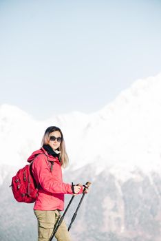 Hiker young woman with trekking poles walking in winter outdoor.