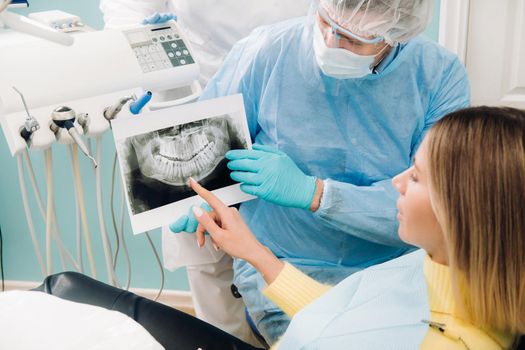 Dentist explaining the details of the X-ray to his patient in the office.