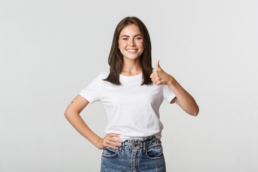 Happy satisfied young woman smiling, showing thumbs-up in approval, like something.