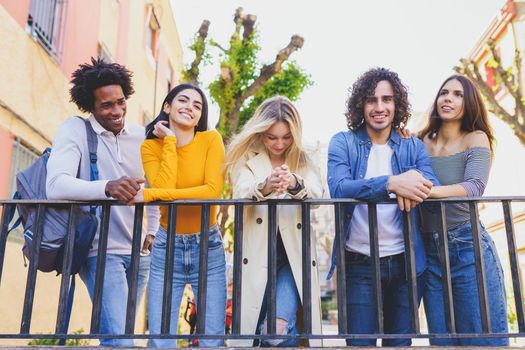 Multiracial group of young people talking together in the street. Students socializing.