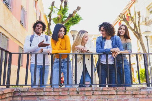 Multiracial group of young people talking together in the street. Students socializing.