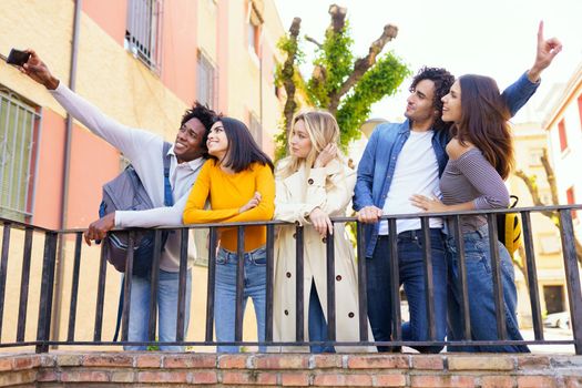 Multi-ethnic group of friends taking a selfie in the street with a smartphone. Young people having fun together.