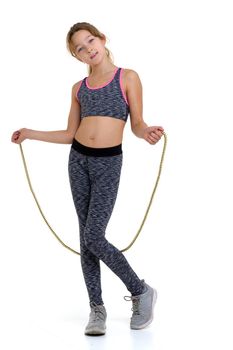 Teenage girl performing exercise with jumping rope. Cheerful girl gymnast wearing sportswear doing sports against white background. Active healthy lifestyle concept