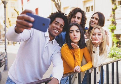 Multi-ethnic group of friends taking a selfie in the street with a smartphone. Young people having fun together.