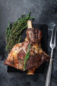 Oven Roasted lamb mutton whole leg with thyme. Black background. Top view.
