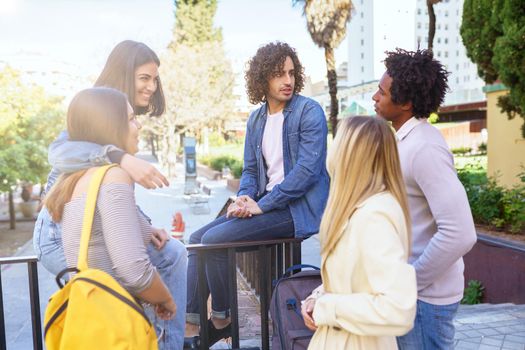 Multi-ethnic group of students talking in the street. Young people having fun together.