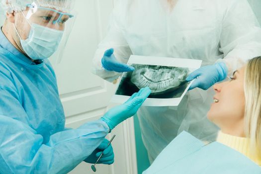 Dentist explaining the details of the X-ray to his patient in the office.