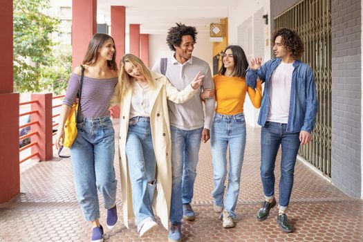 Multi-ethnic group of friends walking together on the street while chatting and having fun.