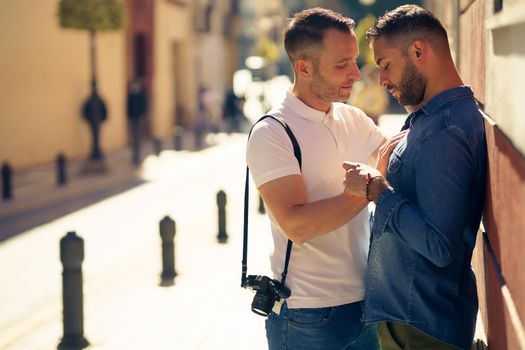 Gay couple tourists in a romantic moment on the street. Homosexual relationship concept.