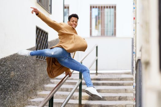 Cuban man jumping for joy over a handrail in the street. Young black guy.