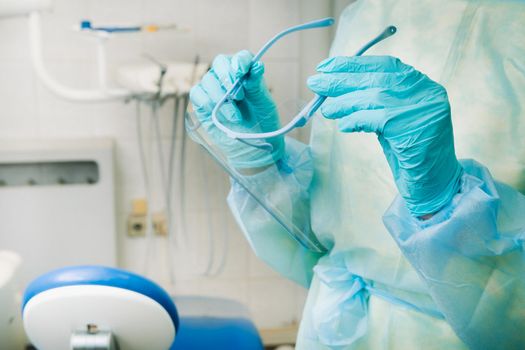 close up of a dentist's hands holding a protective plastic screen in his office.