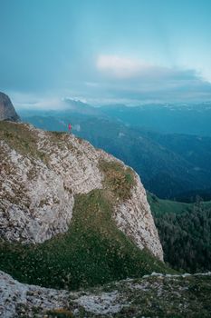 Small figure of outdoor explorer person standing on rocky mountain. Concept of minimal person in massive landscape.