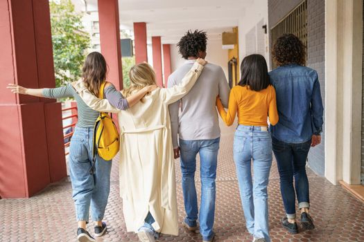 Rear view of multi-ethnic group of friends walking together on the street while chatting and having fun.