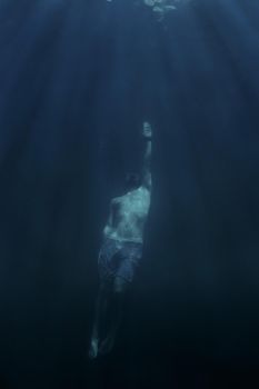 Young man free diver swimming up to the surface.