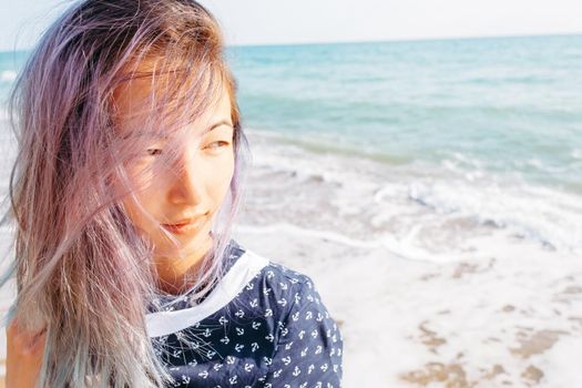 Portrait of smiling girl with violet hair on background of sea.