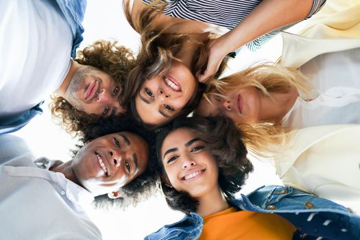 Multi-ethnic group of friends with their heads together in a circle outdoors