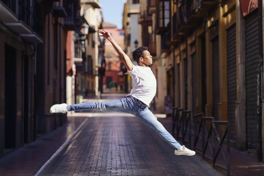 Young black man doing an acrobatic jump in the middle of the street. Cuban guy.