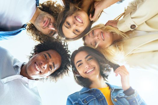 Multi-ethnic group of friends with their heads together in a circle outdoors