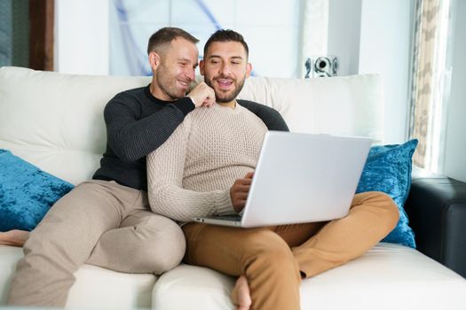 Gay couple consulting their travel plans together with a laptop. Homosexual Lifestyle concept.