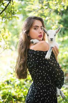 Natural young woman. Virgin girl in village hold yeanling. Sprinf fashion portrait of beautiful woman holding a small lamb