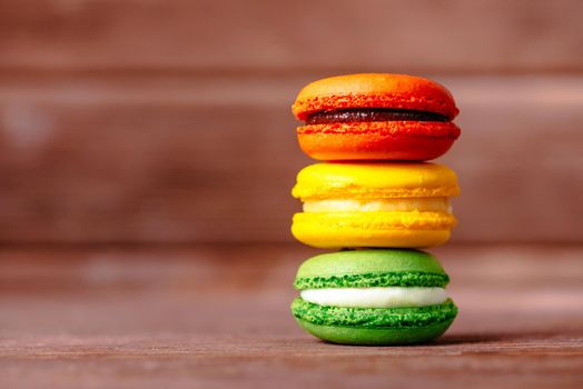 Colorful sweet macaron cookies on a wooden background.