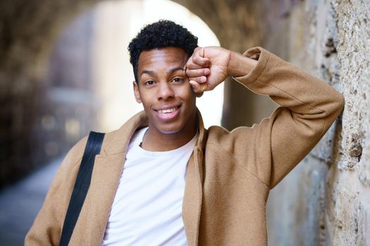 Young black man looking at camera outdoors. Cuban student in urban background.