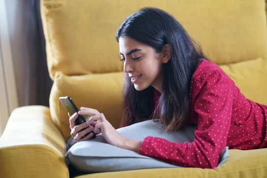 Persian woman at home using smartphone on a couch