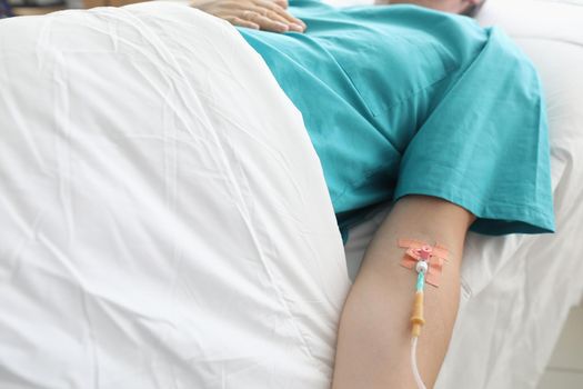 Man lies in hospital with syringe in vein his arm. Treatment an addict in hospital. Needle is fixed with patch to skin in direction vein. Treatment in clinic by administering an intravenous drug