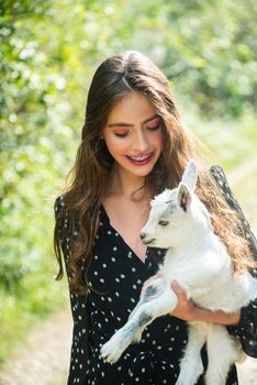 Young beauty woman teen holding a small lamb. Beautiful girl with lamb on a countryside. Love nature