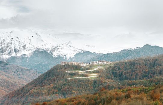 Landscape of health resort and village in the mountains on background of snow peaks.