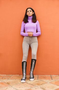 Persian woman standing outdoors on red wall background