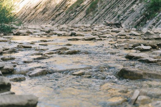 Clean and fresh mountain river or creek flowing among stones in summer.