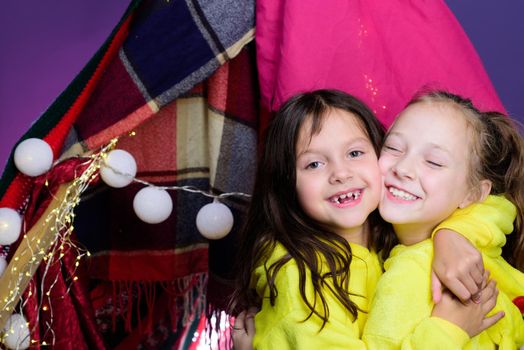 Funny kids face of two cute little children playing in tent at home. Funny lovely kids having fun. Pajamas for kids. Girls having fun tipi house. Girlish leisure
