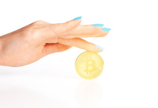 Female hand with glowing gold coin bitcoin on a white background, symbol of crypto currency.