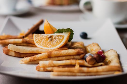 Plate of pancakes nuts and blueberries, oranges pieces. Shrovetide Maslenitsa Butter Week festival meal. Shrove Tuesday. Pancake day.