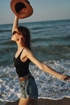 cheerful woman in sunglasses and a hat by the ocean walk summer. High quality photo