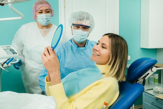 The dentist shows the client the results of his work in the mirror.