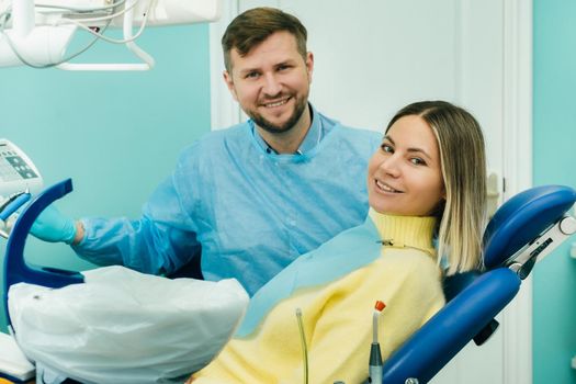 Beautiful girl patient shows the class with her hand while sitting in the Dentist's chair.