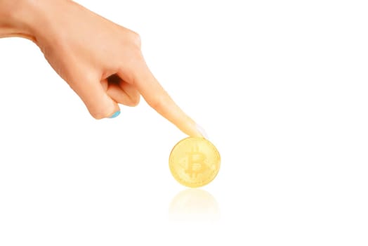 Female hand pointing to glowing gold bitcoin on a white background.