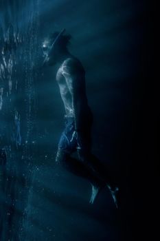 Young man freediver in mask with snorkel swimming underwater near the surface. Concept of magical portal into another world.